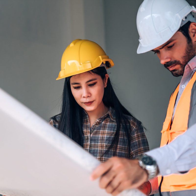 Civil engineer and construction worker manager holding digital tablet and blueprints , talking and planing about construction site.  Cooperation teamwork concept.